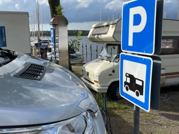 Autocamper parkeret ved Præstø Havn med skilte for autocamperpladser